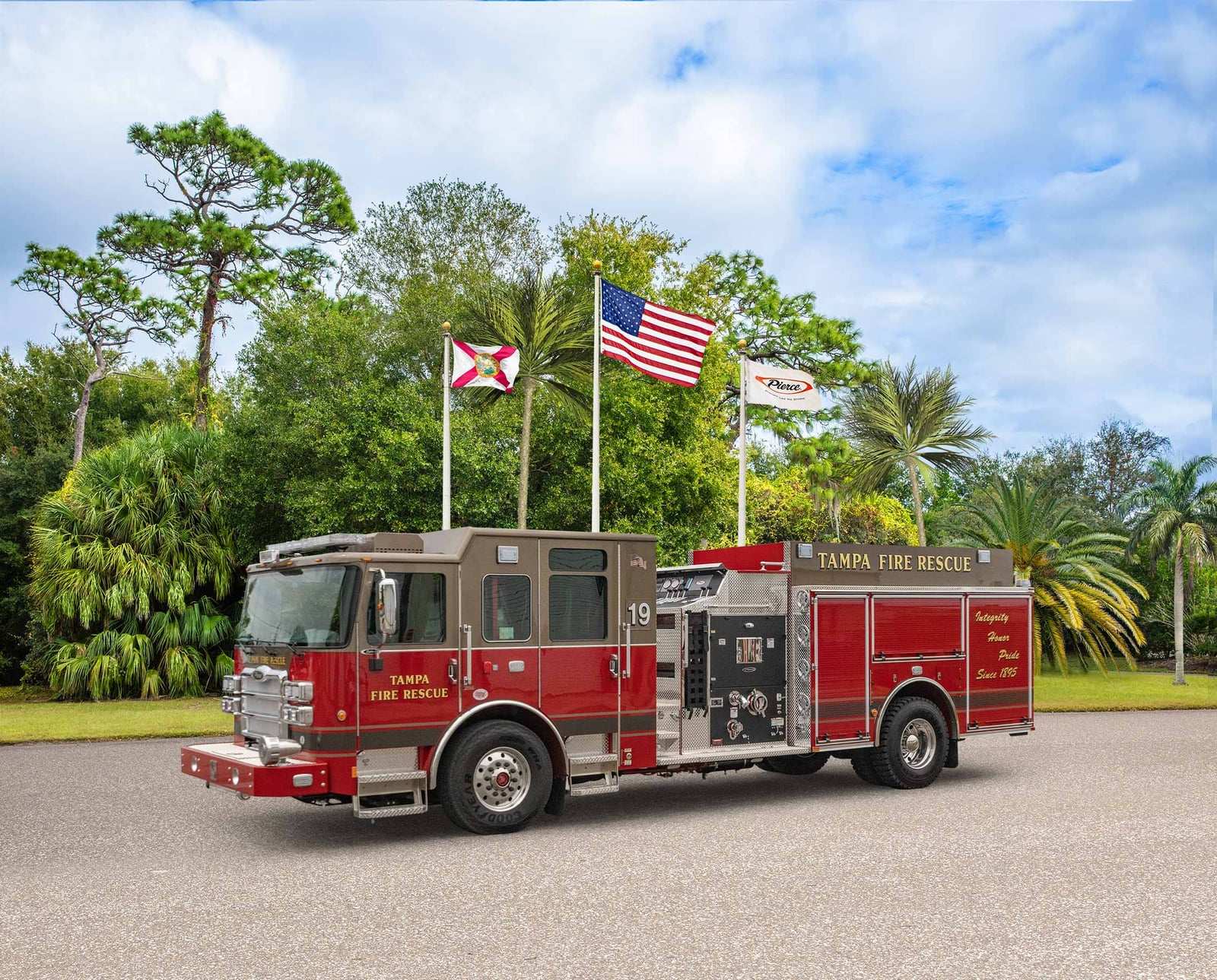 A red and brown Pierce Enforcer pumper lettered Tampa Fire Rescue, number 19, parked on pavement with palm trees and flags behind it.